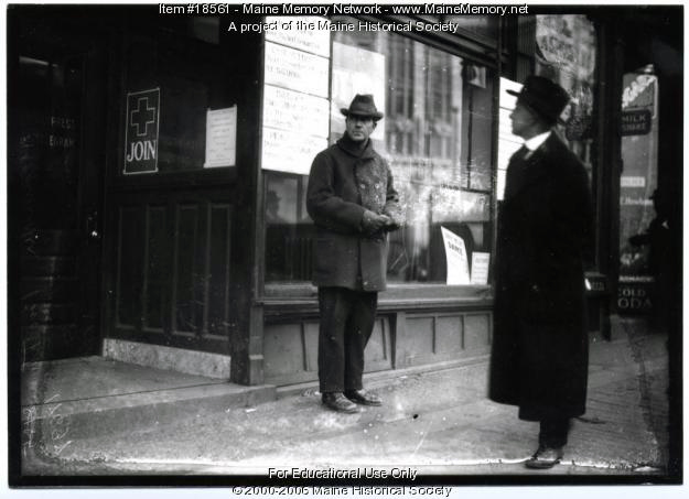 A man stands in front of a storefront window with posters announcing: Buy WSS; Peace plans have made little progress.