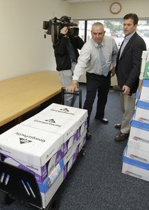 Alaska official Jim Hoff, center, holds a dolly with boxes containing thousands of pages of Sarah Palin's emails as CNN cameraman Jim Castel, left, an