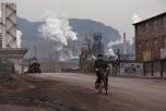 A Chinese worker rides his bike as smoke billows from a nearby steel factory on Nov. 19, 2015 in the Hebei Province, China. (Kevin Frayer/Getty Images)