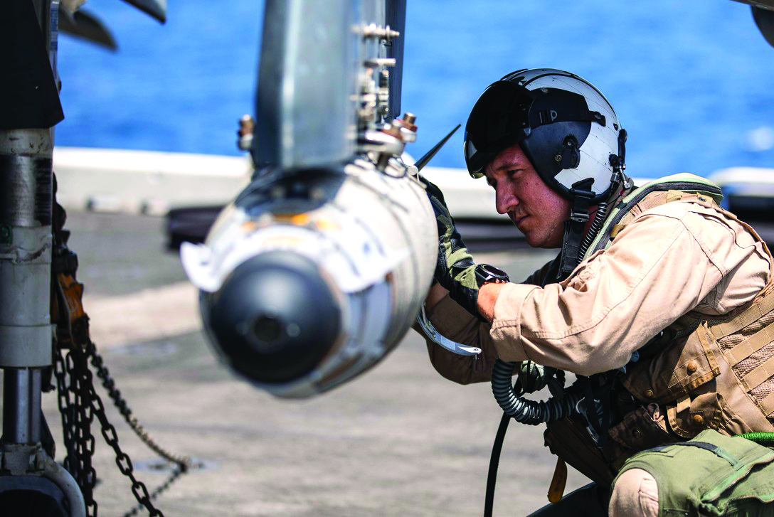 Source: DoD, A Marine Corps aviator inspects munitions on the flight deck of the USS Kearsarge.