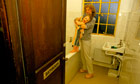 A homeless mother drying her child with a towel in a hostel bathroom. London