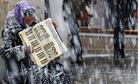 A woman plays an accordion during a snowfall in Buxton
