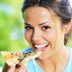 Photo of woman eating a slice of pizza.
