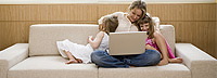 Woman on couch with laptop and children