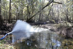 A pipe spews water into a creek