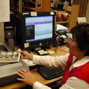 USGS Library employee sitting at computer, scanning in documents.