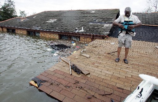 A man tightens his lifevest as he gets ready to be evacauated off his roof in the lower ninth ward after New Orleans is hit by Hurricane Katrina in New Orleans on Monday August 29, 2005