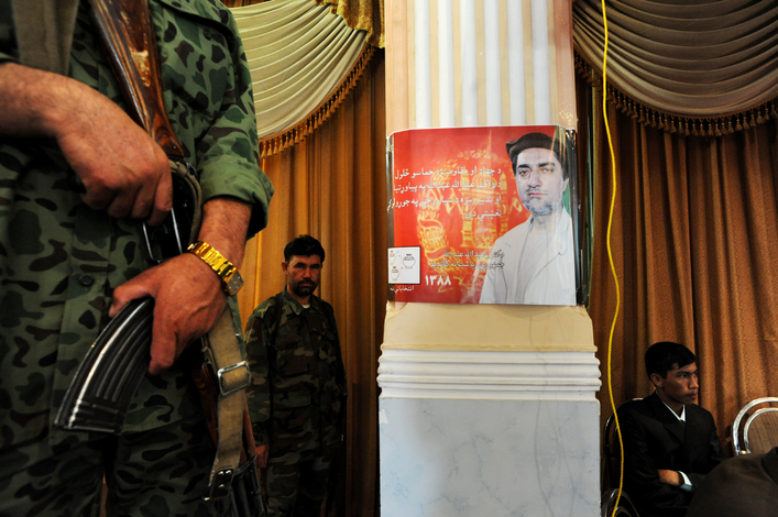 A poster of Afghan presidential candidate Abdullah Abdullah hangs on a column at Ariana Wedding Hall in Kabul, Afghanistan. A security detail kept a watchful eye during Abdullah's speech to a crowd of supporters. Abdullah served as Minister of Foreign Affairs in President Karzai's cabinet from 2002 to 2006. 