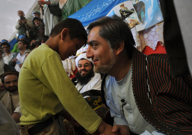 Afghan presidential candidate Abdullah Abdullah, right, greets a young supporter while waiting to take the stage in Maymana, Afghanistan.