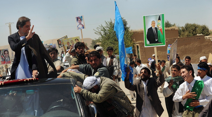 Supporters chase after Afghan presidential candidate Abdullah Abdullah's car, as he heads to a rally in Maymana, Afghanistan.