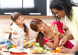 Photo of woman, child, and man cutting and sharing fruits and vegetables