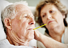 An elderly woman takes an elderly man's temperature