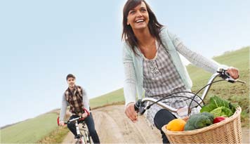 Photo of a man and woman riding bicycles to run their errands with groceries in the basket