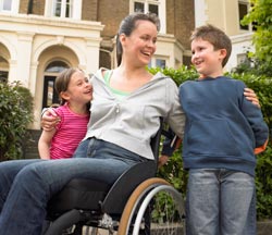 woman in a wheelchair talking to two children