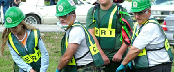 People wearing green hard-hats and green-vest saying "CERT", volunteers for a CERT Team, working to clean up
