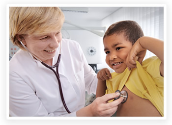 A doctor listens to the heartbeat of a smiling young boy