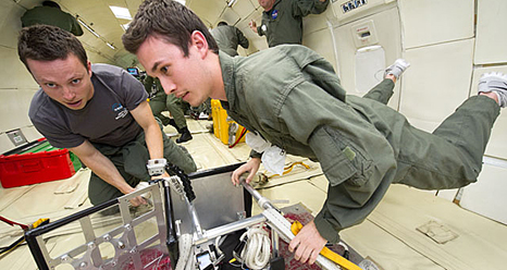 Boston University students Joshua Koerpel and Christopher Hoffman test a solar array deployment system for use on CubeSats as they float in very low gravity during a parabolic flight in Zero-G Corporation's modified Boeing 727 jetliner.