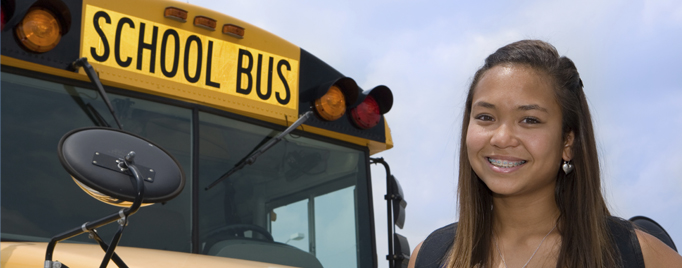 Girl standing in front of a school bus