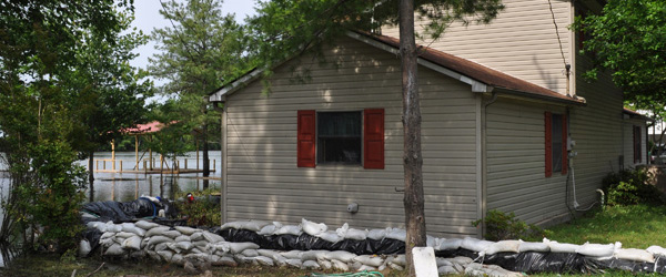 A home with sandbags around it with rising flood waters.