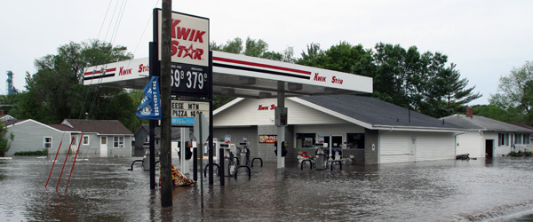 Flood waters surrounding a row of business storefronts.