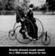 Smartly dressed couple seated on a 1886-model bicycle for two