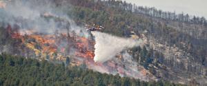 Helicopter spreading water over a forest fire.