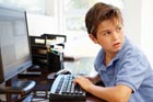 A young boy sits at a computer