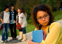 A girl stands apart from her classmates