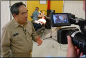 former Acting Surgeon General RADM Kenneth P. Moritsugu is interviewed by Public Affairs Office personnel at a pierside temporary dental clinic while Corps dental hygienists provide care.