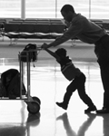 Photo: Travelers pushing a luggage cart.