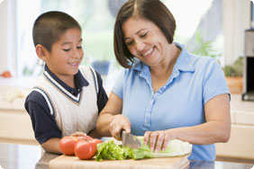 Smiling Woman and Little Boy Cutting Vegetables