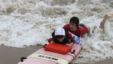 Austin Bramson takes a ride on a surfboard with the help of a Best Day at the Beach volunteer. (VOA/D. Gruenbaum)