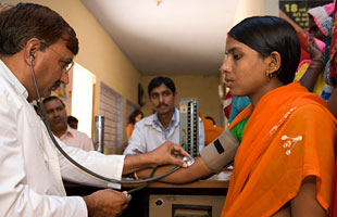 A doctor takes a woman's blood pressure, India.