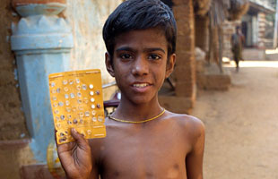 A 12 year old leprosy patient in Orissa, India, proudly holds up his MDT treatment. He has just completed his 11th monthly dose and is looking forward to completing the treatment.