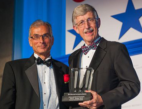 Dr. Young and Dr. Collins holding a glass award on a stage