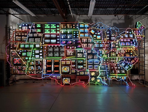 Image description: A moment in time from the multi-media artwork &#8220;Electronic Superhighway: Continental U.S., Alaska, Hawaii&#8221; by Nam June Paik in 1995. The 40 foot-long piece is constructed of 336 televisions, 50 DVD players, 3,750 feet of cable, and 575 feet of multi-color neon tubing.
According to the Smithsonian, Nam June Paik is hailed as the “father of video art” and credited with the first use of the term “information superhighway” in the 1970s. He recognized the potential for media collaboration among people in all parts of the world, and he knew that media would completely transform our lives.
Electronic Superhighway, currently on display at the Smithsonian American Art Museum, is a testament to the ways media defined one man’s understanding of a diverse nation.
Learn more about the piece and the artist (PDF document). For teachers, there is a curriculum based on the artwork.
Photo from the Smithsonian American Art Museum