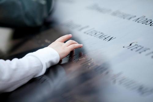 Image description: A child touches the name of someone who died on September 11, 2011. The name is part of the memorial at the National September 11 Memorial and Museum. Find a name on the memorial.
Photo by Jin Lee. View more of Lee&#8217;s photos of touching moments at the memorial.