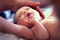 Fotografía de un recién nacido siendo acariciado por las manos de una mujer