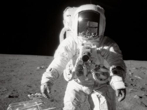Image description: Astronaut Alan L. Bean pauses near a tool carrier during the Apollo 12 spacewalk on the moon&#8217;s surface. Commander Charles Conrad, Jr. took the black-and-white photo and is reflected in Bean&#8217;s helmet visor.
Photo by NASA