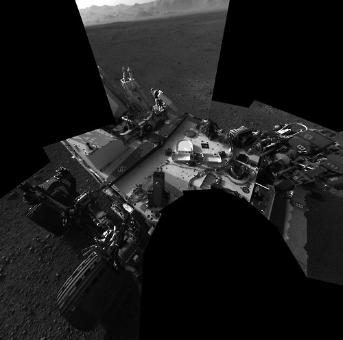 Image description: I, Robot. This self-portrait by the NASA Curiosity rover on the surface of Mars is a mosaic made up of 8 images taken on August 8. Curiosity is using these first days after landing to check its systems.
The back of the rover can be seen at the top left of the image, and two of the rover&#8217;s right side wheels can be seen on the left. Part of the pointy rim of Gale Crater forms the lighter color strip in the background. Bits of gravel, about 0.4 inches (1 centimeter) in size, are visible on the deck of the rover.