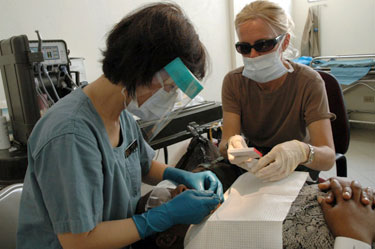 Dentist LCDR Janice Kim (left) and an Air Force dental hygienist work together on a patient in Port-au-Prince, Haiti.