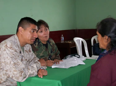 LT Katherine Morris, a physician assistant, consults with a patient while a U.S. Marine looks on.