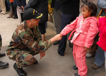 While in Peru as part of Operation Continuing Promise, CDR John Eckert, a scientist, greets a pediatric patient at a clinic.
