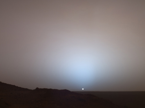 Image description: On May 19, 2005, NASA&#8217;s Mars Exploration Rover Spirit captured this stunning view as the Sun sank below the rim of Gusev crater on Mars. This Panoramic Camera mosaic was taken around 6:07 in the evening of the rover&#8217;s 489th Martian day, or sol.
From NASA:
Sunset and twilight images are occasionally acquired by the science team to determine how high into the atmosphere the Martian dust extends, and to look for dust or ice clouds. Other images have shown that the twilight glow remains visible, but increasingly fainter, for up to two hours before sunrise or after sunset. The long Martian twilight (compared to Earth&#8217;s) is caused by sunlight scattered around to the night side of the planet by abundant high altitude dust. Similar long twilights or extra-colorful sunrises and sunsets sometimes occur on Earth when tiny dust grains that are erupted from powerful volcanoes scatter light high in the atmosphere.
Photo by: NASA/JPL/Texas A&amp;M/Cornell
