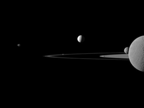 Image description: NASA&#8217;s Cassini spacecraft recently captured this portrait of five of Saturn&#8217;s moons poised along the planet&#8217;s rings, nearly a billion miles away from Earth. From left to right are Janus, Pandora, Enceladus, Mimas and finally Rhea, bisected by the right side of the frame.
Photo by NASA.