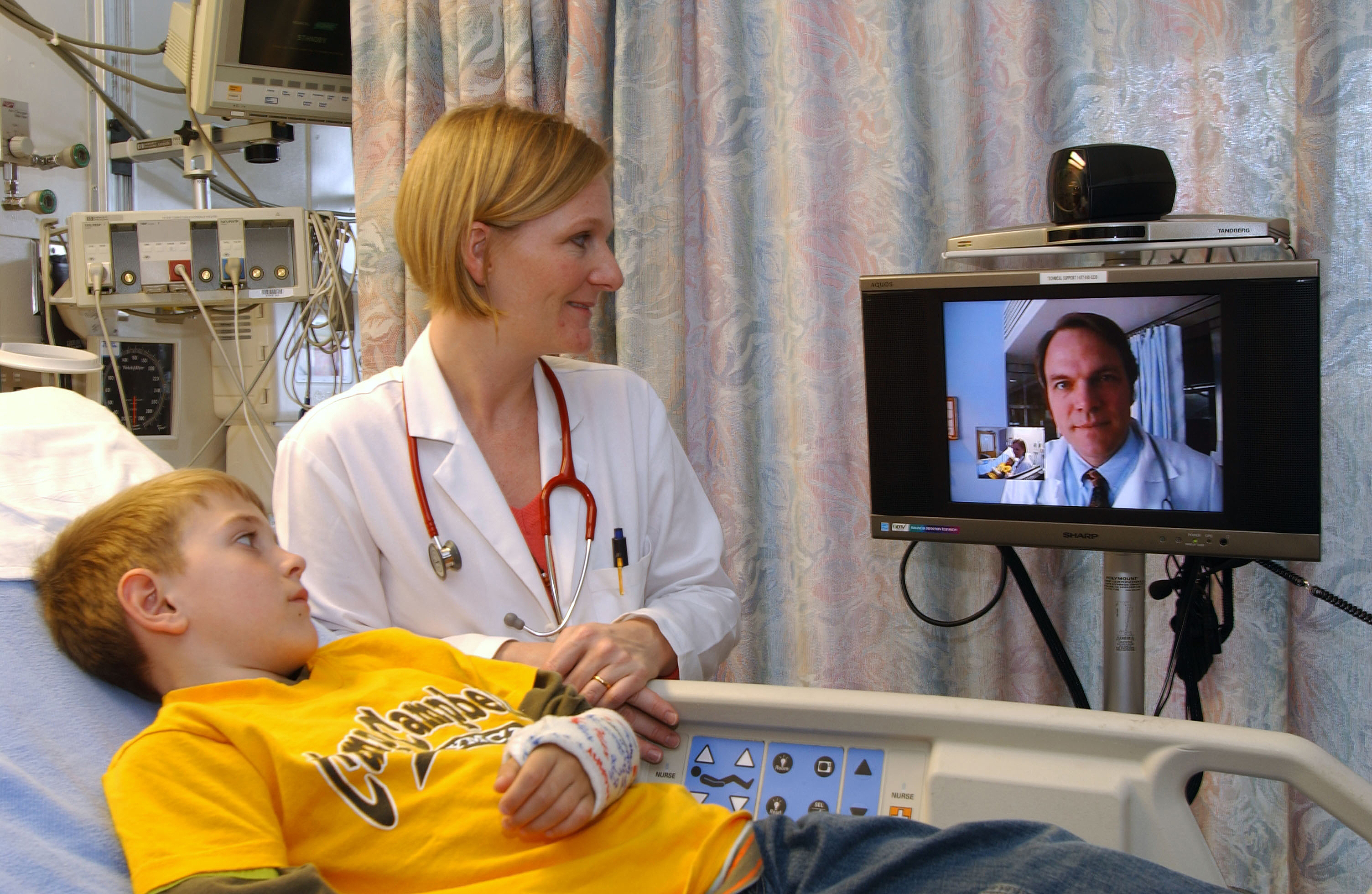 Figure1A - An example of a Teleconsultation. A physician at the distant hospital consults with a subspecialist, over a secure video connection, on the treatment of a child. 