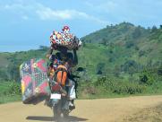 A fair-goer carries bundles of goods home on a motorbike.