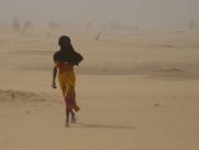 Woman walks through the desert outside a refugee camp in Chad