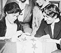 Women sewing stars on suffrage flag
