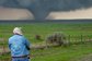 Researcher in field measuring large tornado in distance